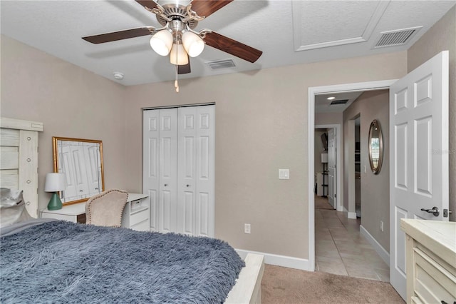 carpeted bedroom featuring ceiling fan, a closet, and a textured ceiling