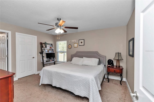 carpeted bedroom featuring ceiling fan and a textured ceiling