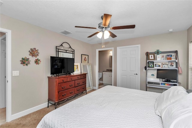 bedroom with ensuite bathroom, light colored carpet, a textured ceiling, and ceiling fan