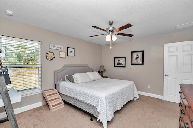 bedroom featuring ceiling fan, light colored carpet, and a textured ceiling