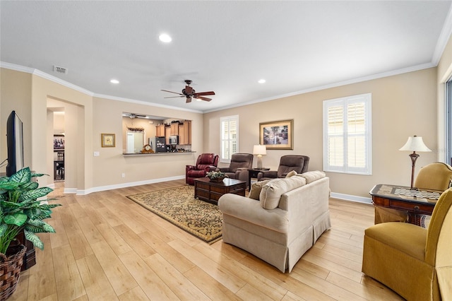 living room featuring ornamental molding, a wealth of natural light, ceiling fan, and light hardwood / wood-style flooring