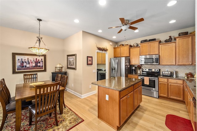 kitchen with tasteful backsplash, a center island, hanging light fixtures, light hardwood / wood-style flooring, and stainless steel appliances