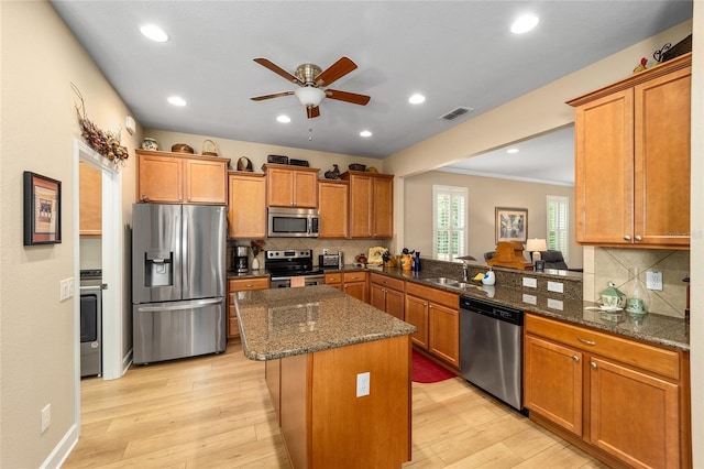 kitchen featuring sink, stainless steel appliances, light hardwood / wood-style floors, kitchen peninsula, and dark stone counters