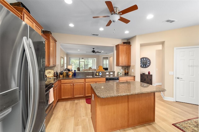 kitchen with a center island, light wood-type flooring, appliances with stainless steel finishes, kitchen peninsula, and backsplash