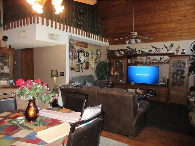 living room with hardwood / wood-style flooring, ceiling fan with notable chandelier, and high vaulted ceiling