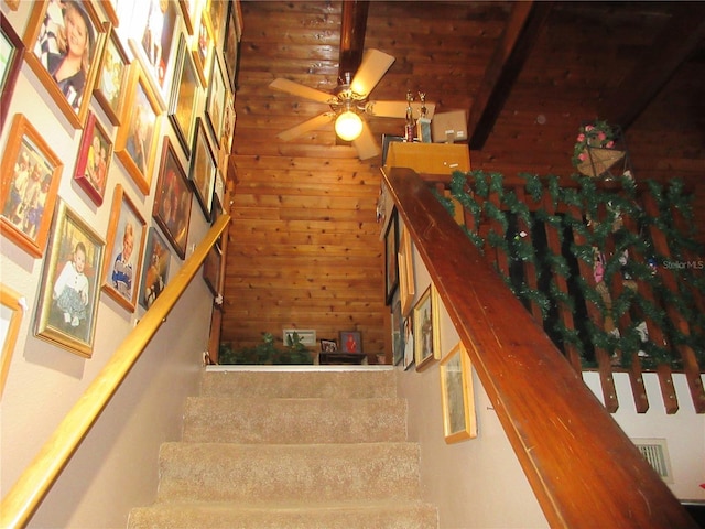 stairway featuring ceiling fan and wood walls