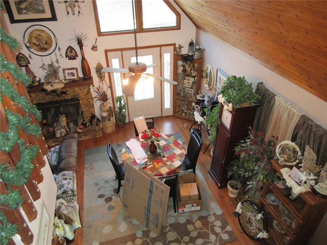 dining room featuring vaulted ceiling, ceiling fan, a fireplace, and light hardwood / wood-style floors