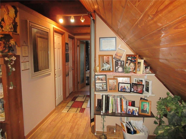 hallway with wood ceiling, track lighting, lofted ceiling, and light wood-type flooring