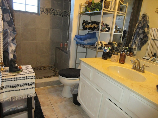 bathroom featuring vanity, toilet, tile patterned flooring, and a tile shower