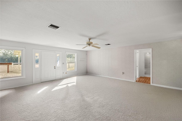 unfurnished living room featuring ceiling fan, light colored carpet, and a textured ceiling