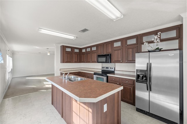 kitchen featuring sink, stainless steel appliances, ornamental molding, a textured ceiling, and a center island with sink