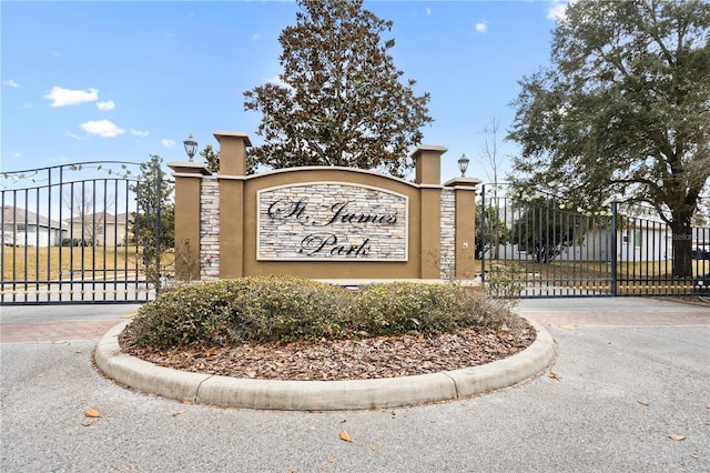 community / neighborhood sign with driveway and a gate