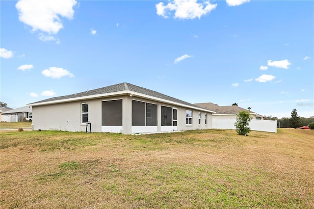 rear view of house with a lawn and a sunroom