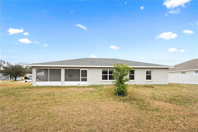 rear view of house with a yard, fence, a sunroom, and stucco siding