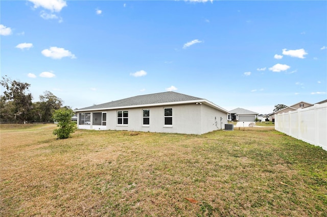 rear view of house with a yard, central AC, and fence