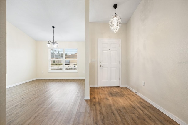 interior space featuring baseboards, wood finished floors, and a chandelier