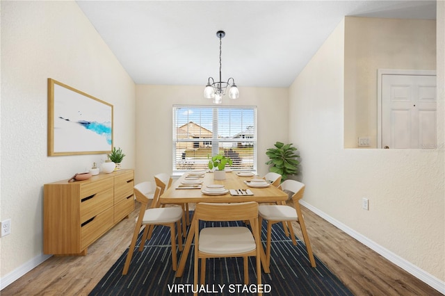 dining area with lofted ceiling, light wood-style flooring, a notable chandelier, and baseboards