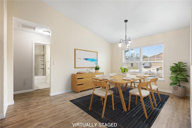 dining area with baseboards, an inviting chandelier, wood finished floors, and vaulted ceiling