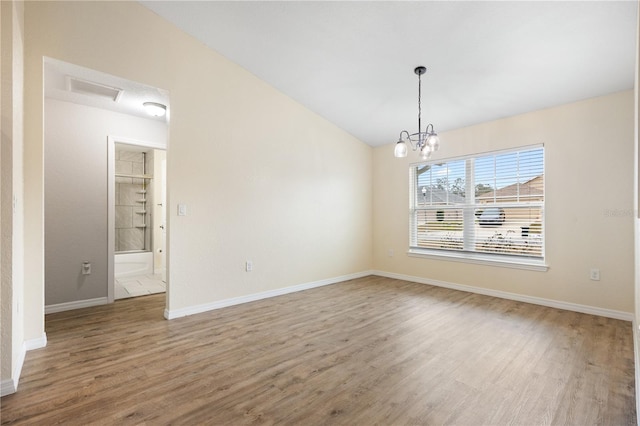 empty room with a chandelier, baseboards, lofted ceiling, and wood finished floors