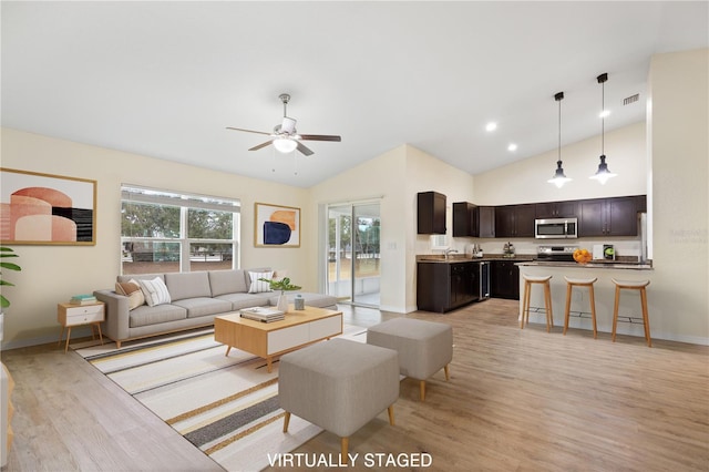 living room featuring a ceiling fan, visible vents, light wood finished floors, and high vaulted ceiling