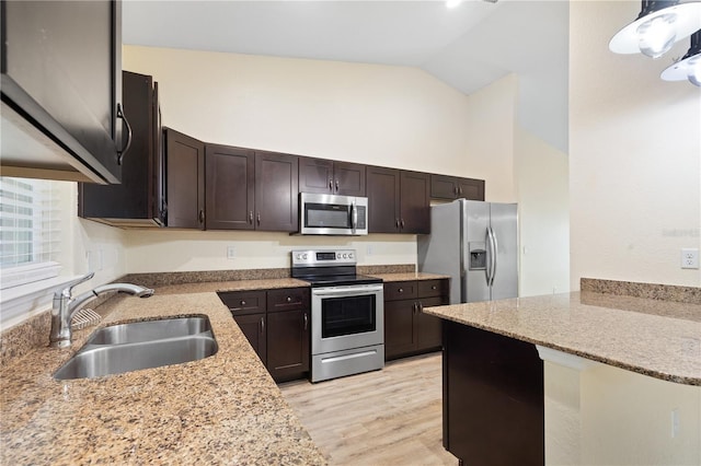 kitchen featuring dark brown cabinets, light stone countertops, light wood-type flooring, stainless steel appliances, and a sink