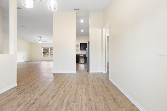 unfurnished living room with light wood-type flooring, baseboards, visible vents, and a ceiling fan