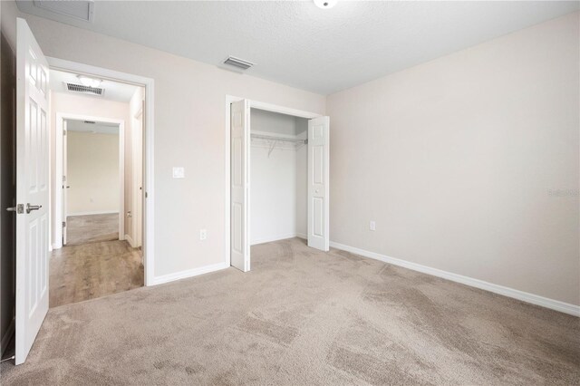 unfurnished bedroom featuring visible vents, carpet, and a closet