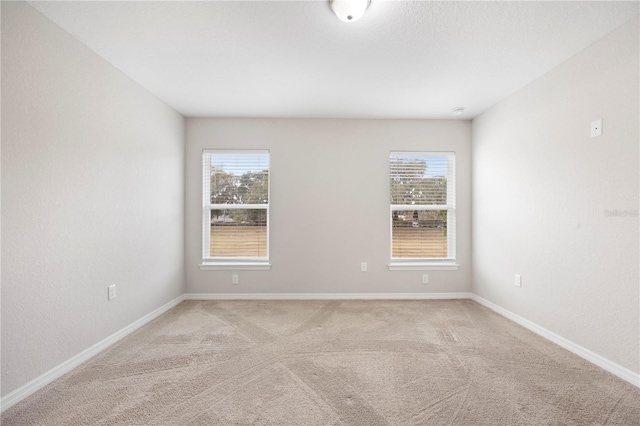 unfurnished room with light colored carpet and baseboards