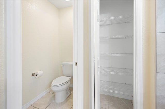 bathroom featuring tile patterned flooring, toilet, and baseboards