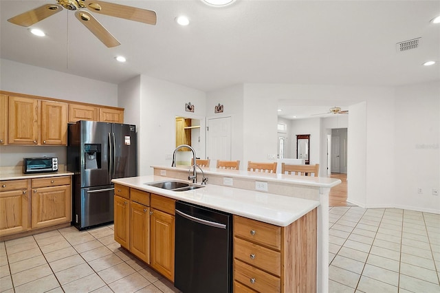 kitchen featuring stainless steel refrigerator with ice dispenser, sink, light tile patterned floors, dishwasher, and an island with sink