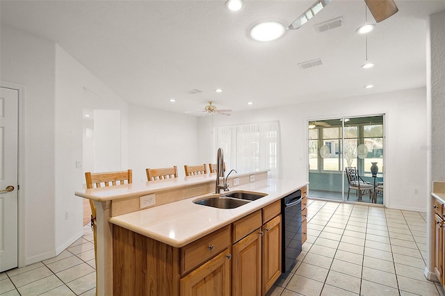 kitchen featuring sink, light tile patterned floors, a kitchen breakfast bar, black dishwasher, and an island with sink