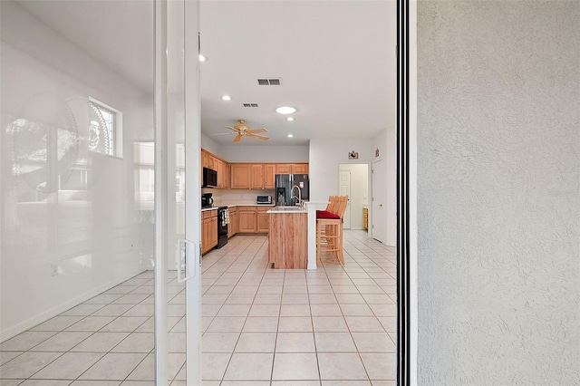 kitchen with range with electric cooktop, light tile patterned flooring, an island with sink, a kitchen breakfast bar, and stainless steel refrigerator with ice dispenser