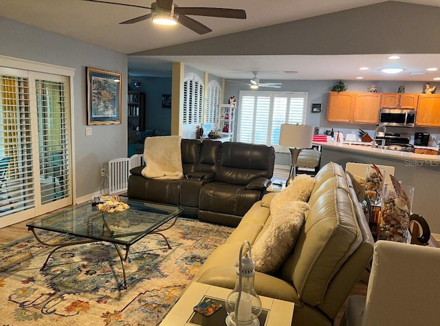 living room with ceiling fan, vaulted ceiling, and light wood-type flooring