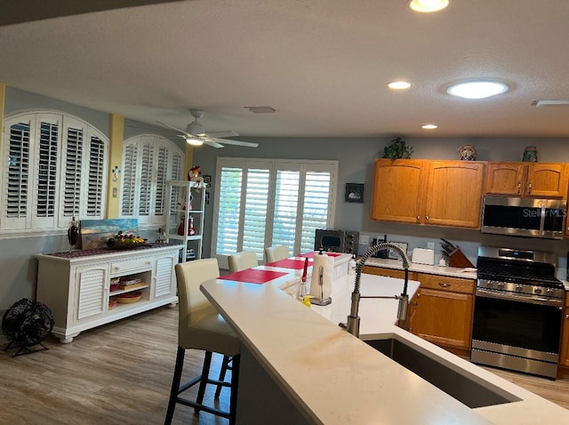 kitchen with appliances with stainless steel finishes, a kitchen breakfast bar, sink, and hardwood / wood-style floors