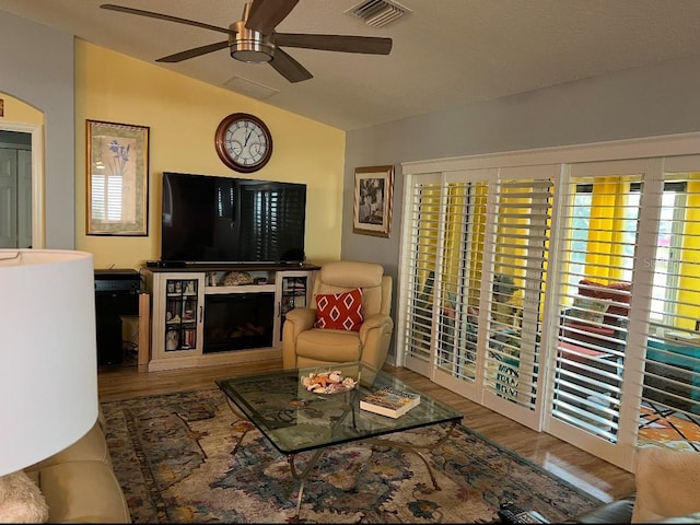 living room with lofted ceiling, hardwood / wood-style flooring, and ceiling fan