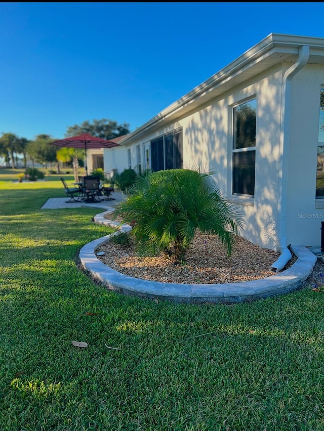 view of side of property with a patio area and a lawn