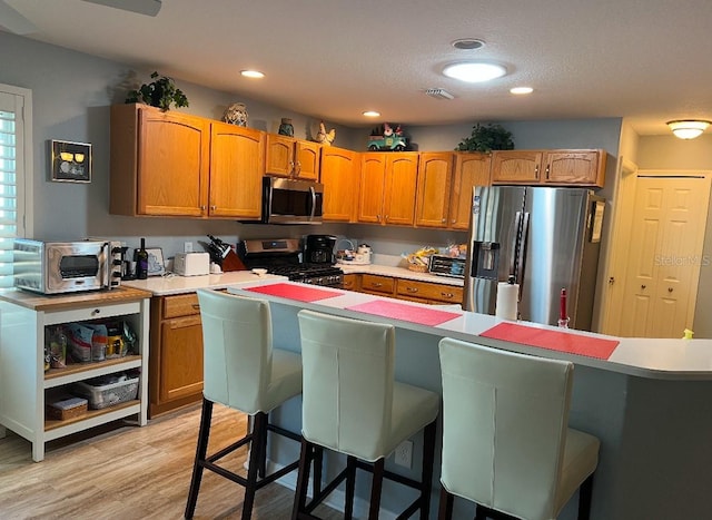 kitchen with stainless steel appliances, a kitchen breakfast bar, and light hardwood / wood-style floors