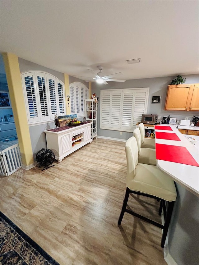 living area with light wood-style flooring, baseboards, and ceiling fan