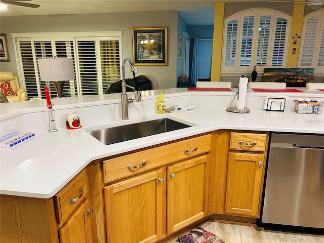 kitchen featuring brown cabinetry, light countertops, a sink, and stainless steel dishwasher