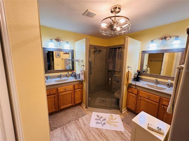 full bath featuring a shower stall, a textured ceiling, visible vents, and a sink