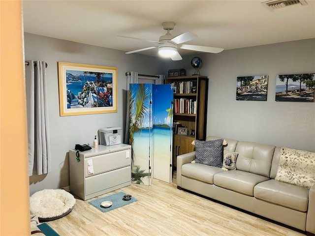 living area with wood finished floors, visible vents, and a ceiling fan