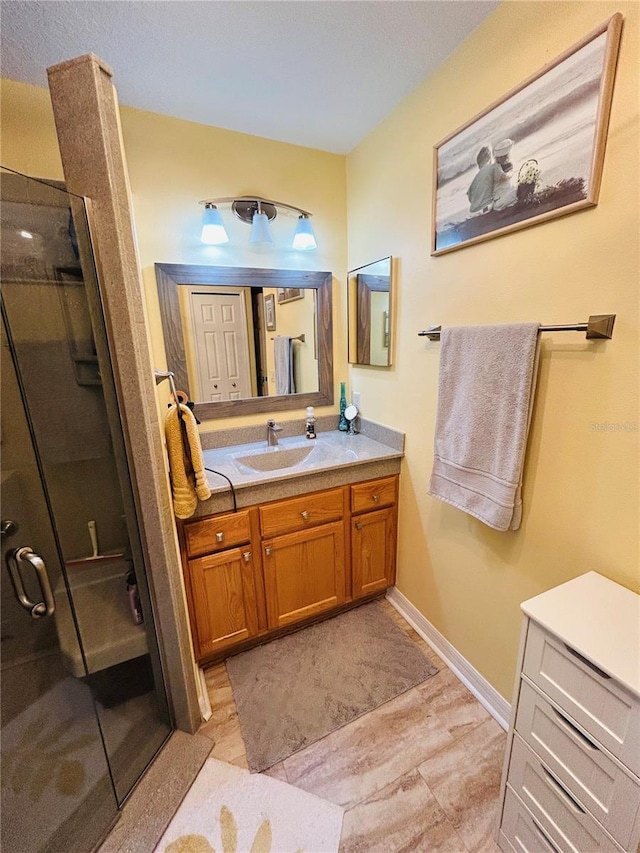 full bathroom with a stall shower, vanity, and baseboards