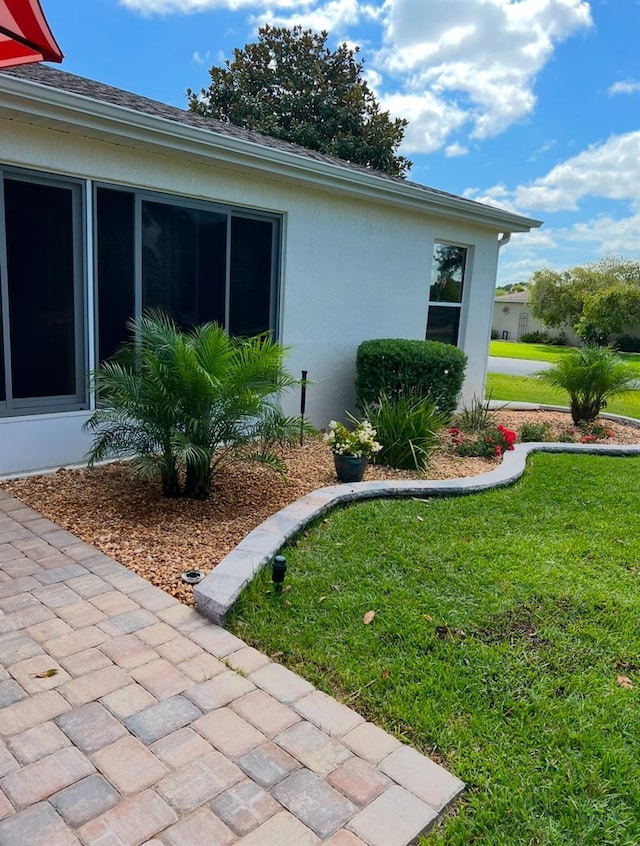 view of side of home with a lawn and stucco siding