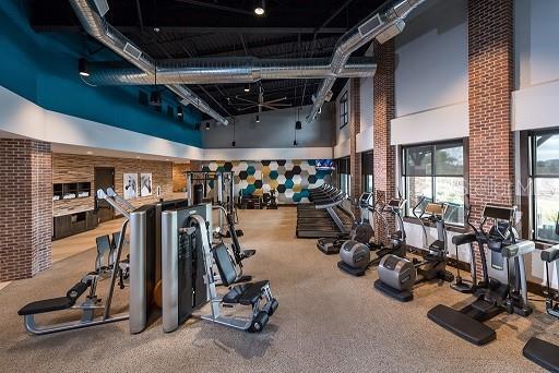exercise room with a towering ceiling, brick wall, and carpet