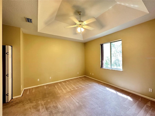 carpeted empty room featuring ceiling fan and a tray ceiling