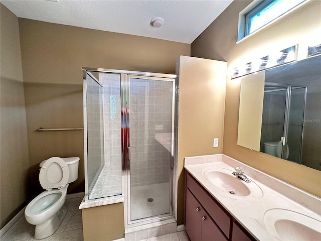 bathroom with a shower with door, vanity, tile patterned floors, and toilet