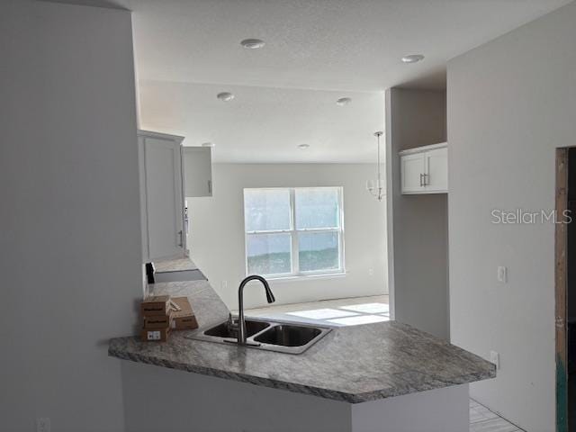 kitchen with kitchen peninsula, sink, and white cabinets