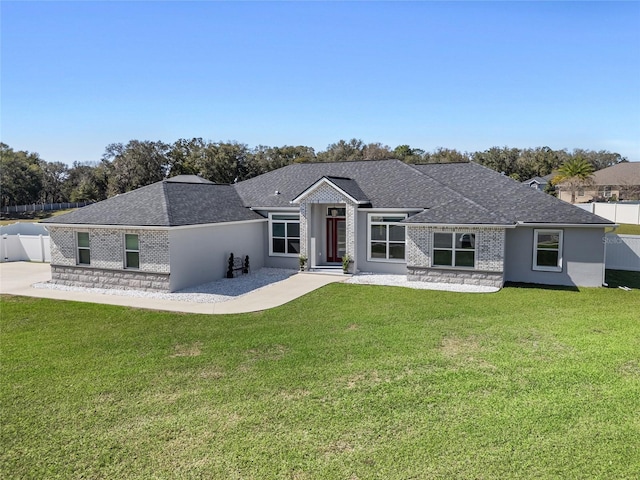 view of front facade featuring roof with shingles, fence, and a front yard