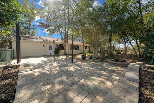 rear view of property featuring a patio, an outdoor fire pit, and fence