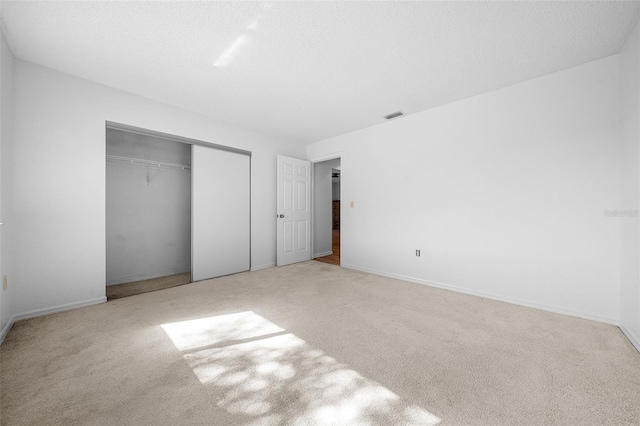 unfurnished bedroom featuring carpet flooring, visible vents, a closet, and a textured ceiling